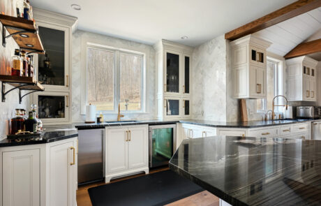 Kitchen with tiled walls, white cabinets and black marble countertop.