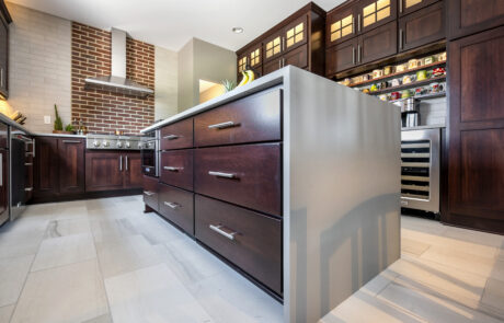 Kitchen island with drawers, dark wood and white waterfall countertop.